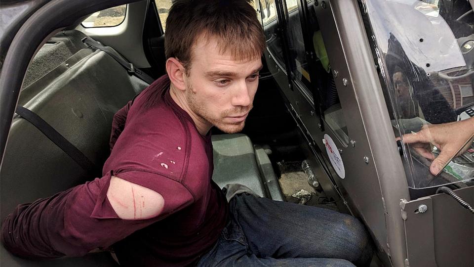 In this photo released by the Metro Nashville Police Department, Travis Reinking sits in a police car after being arrested in Nashville, Tenn., April 23, 2018.