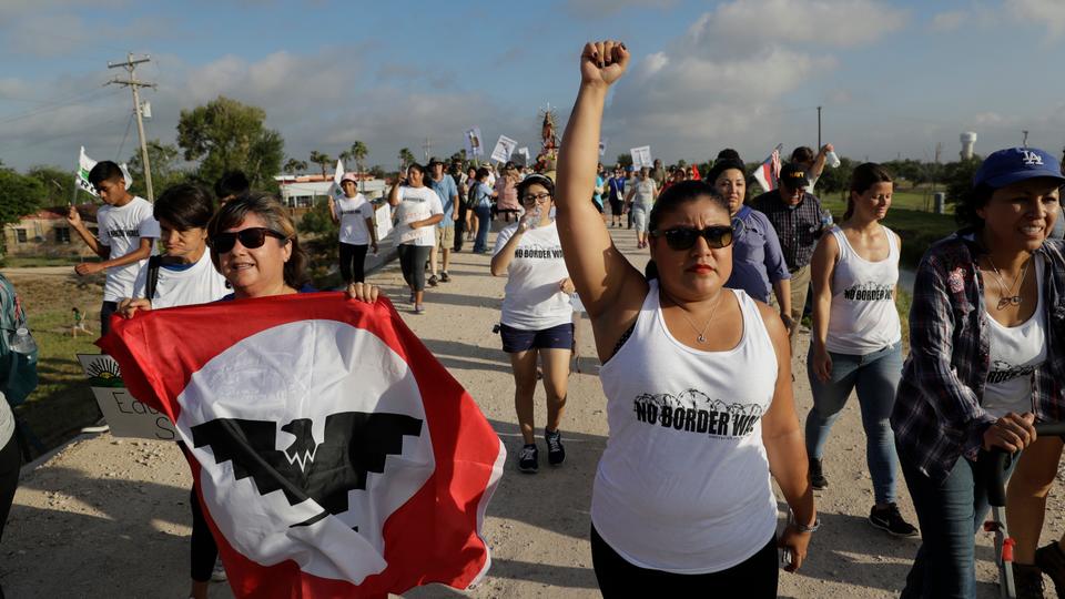 Diane Delgado raises her fist as she chants during a march along a levee toward the Rio Grande to oppose the wall the US government wants to build on the river separating Texas and Mexico, Saturday, August 12, 2017, in Mission, Texas. The area would be the target of new barrier construction under the Trump administration's current plan.