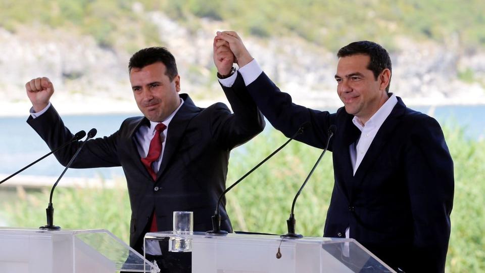 Greek Prime Minister Alexis Tsipras, right, and Macedonian Prime Minister Zoran Zaev join hands before the signing of an accord to settle a long dispute over the former Yugoslav republic's name, in the Greek village of Psarades on June 17, 2018.