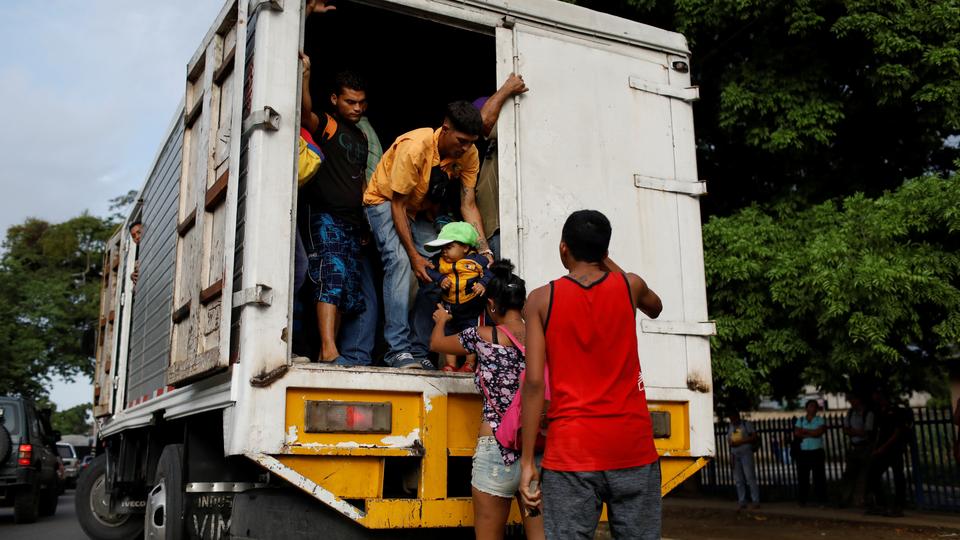 A man helps a kid to get on a cargo truck used as public transportation in Valencia, Venezuela July 11, 2018. Picture taken July 11, 2018.