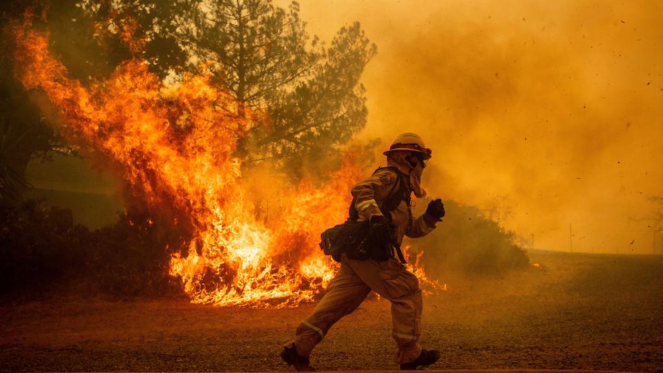 A firefighter runs while trying to save a home as a wildfire tears through Lakeport, Calif.ornia. July 31, 2018.