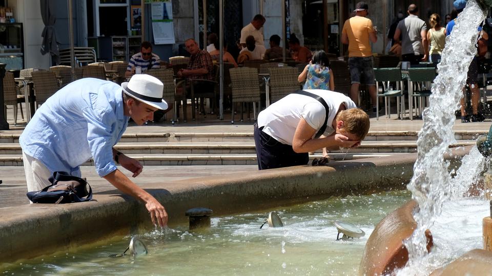 Tourists cool off at a fountain during the heatwave at the Virgin Square in Valencia, Spain, on August 3, 2018.