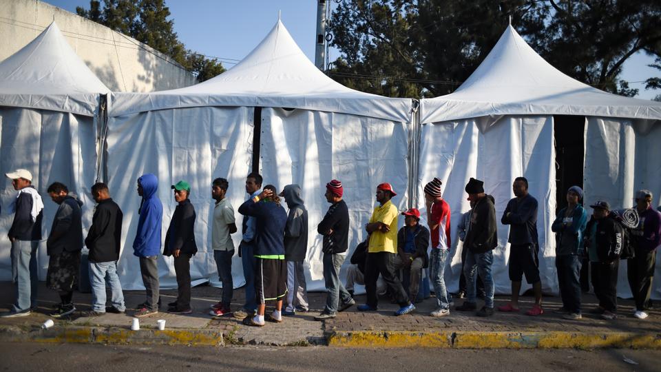 Central American migrants taking part in a caravan towards the US, queue for food at a shelter set up at the Sports City in Mexico City on November 8, 2018.