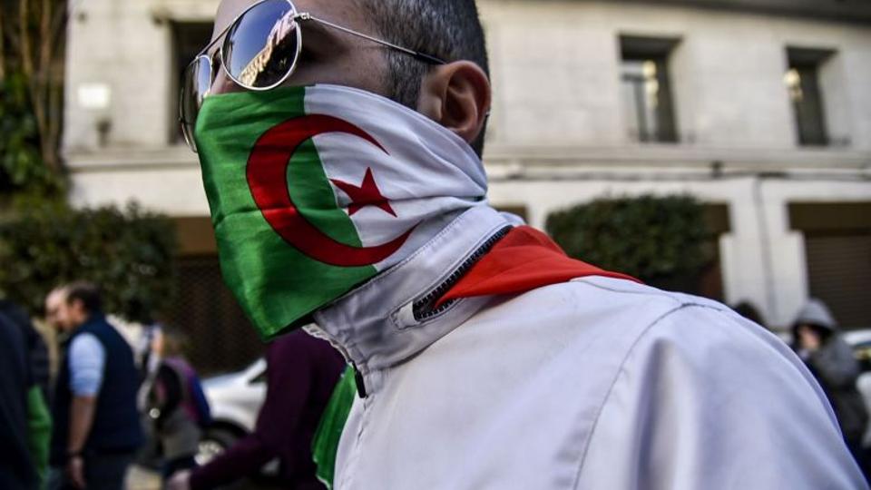 An Algerian protester wearing an Algerian flag as a face-covering marches in the capital Algiers. PHOTO: AFP