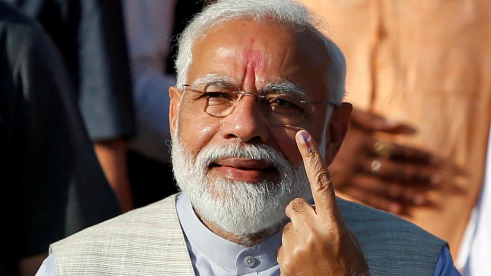 Prime Minister Narendra Modi shows his ink-marked finger outside a polling station during the third phase of the general election in Ahmedabad on April 23, 2019.