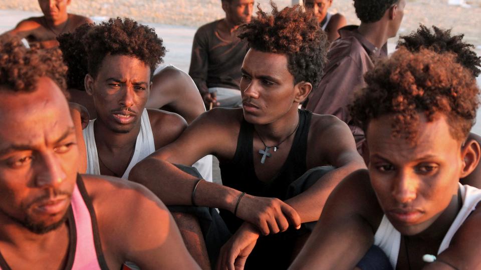 Rescued migrants sit on the coast of Khoms, some 100 kilometres from the Libyan capital Tripoli. July 26, 2019.