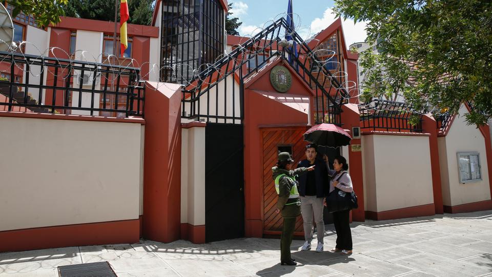 A police officer speaks with two persons in front of the Spain's embassy in La Paz, Bolivia on December 30, 2019.