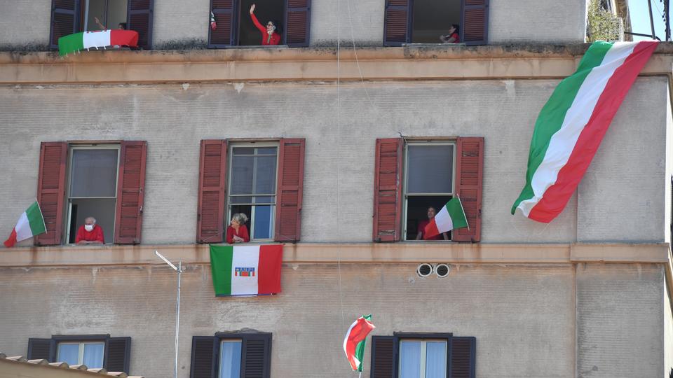 Residents with Italian flags in the Garbatella district of Rome participate on April 25, 2020 in a 'Liberation Day' flashmob with people singing the Italian partizan song 'Bella Ciao' from their window or balcony, during closing from the country destined to stop the spread of the Covid-19 infection, caused by the new coronavirus.