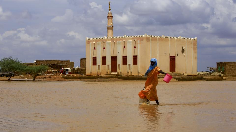 A Sudanese woman crosses a flooded area, as a result of flooding and torrential rain, in the town of Osaylat, 50 km southeast of the capital Khartoum, on August 6, 2020,