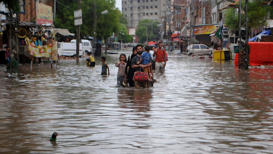 People wade through a flooded road after heavy rainfalls in Hyderabad, Pakistan, August. 25, 2020.