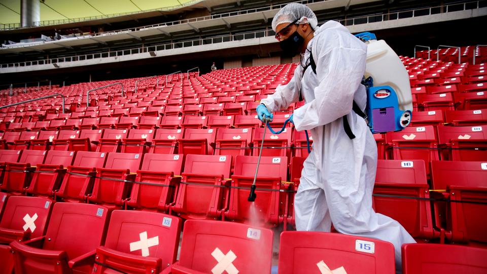 A Guadalajara staff member disinfects the stands before the start of a Mexican Apertura tournament football match in Guadalajara, Jalisco state, Mexico, on August 29, 2020, during the Covid-19. pandemic.