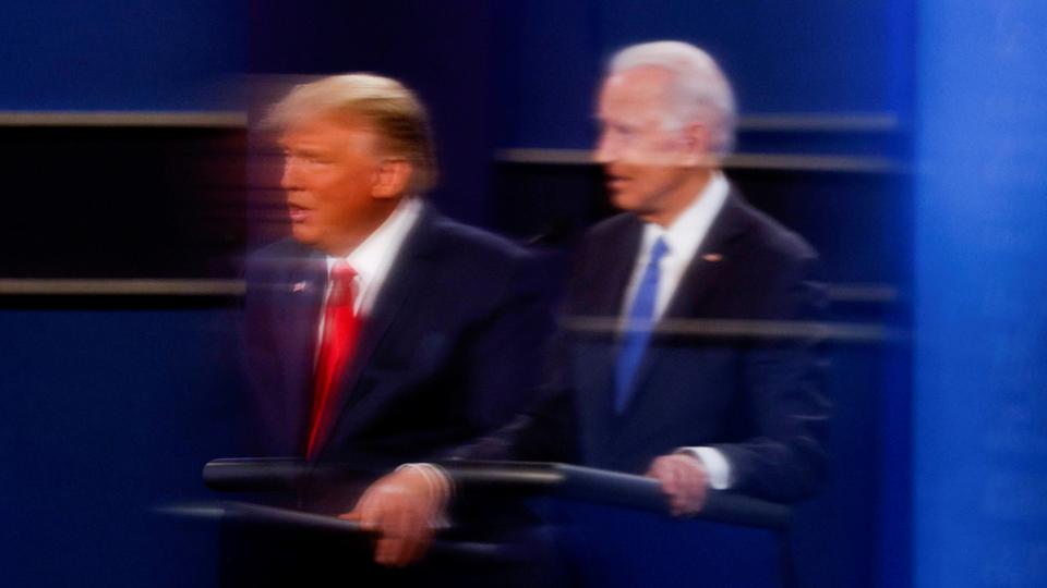 In this file photo, US President Donald Trump and President-elect Joe Biden are reflected in the plexiglass protecting a TV camera operator from coronavirus in Nashville, Tennessee, US, October 22, 2020.