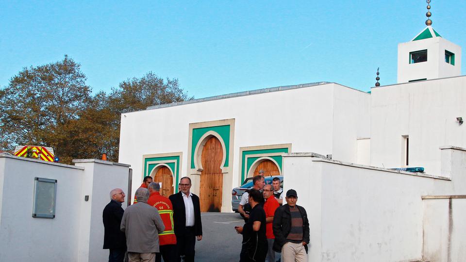 Local residents, firemen, and police officers stand outside a mosque after an incident where two elderly men were seriously injured in Bayonne, southwestern France, on October 28, 2019.