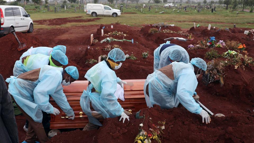 Funeral workers wearing personal protective equipment carry a casket during the burial of a COVID-19 victim at the Olifantsvlei cemetery, south-west of Joburg, South Africa January 6, 2021.