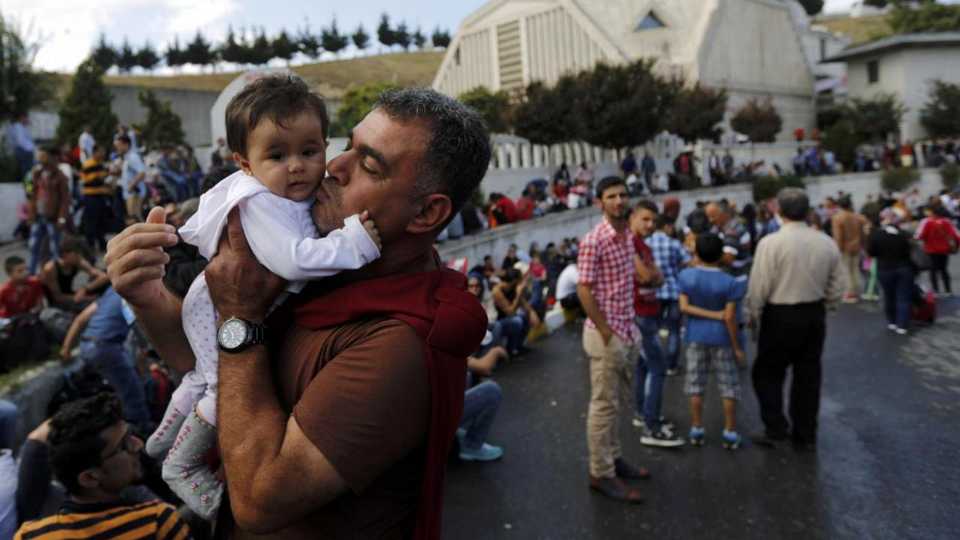 Syrian refugee kisses his 7-month-old daughter as they wait at the main bus station in Istanbul, Turkey, September 15, 2015.