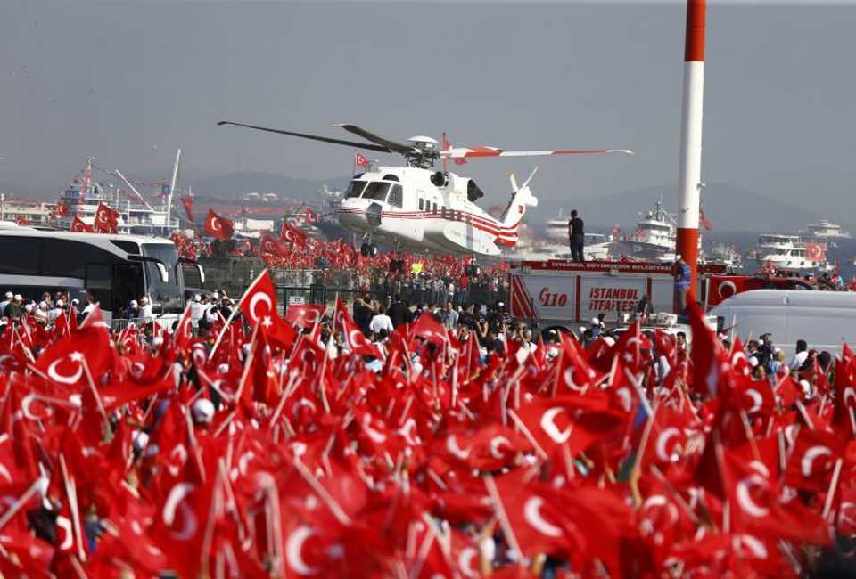 A helicopter flies over as people wave Turkey's national flags during the Democracy and Martyrs Rally in Istanbul. Reuters