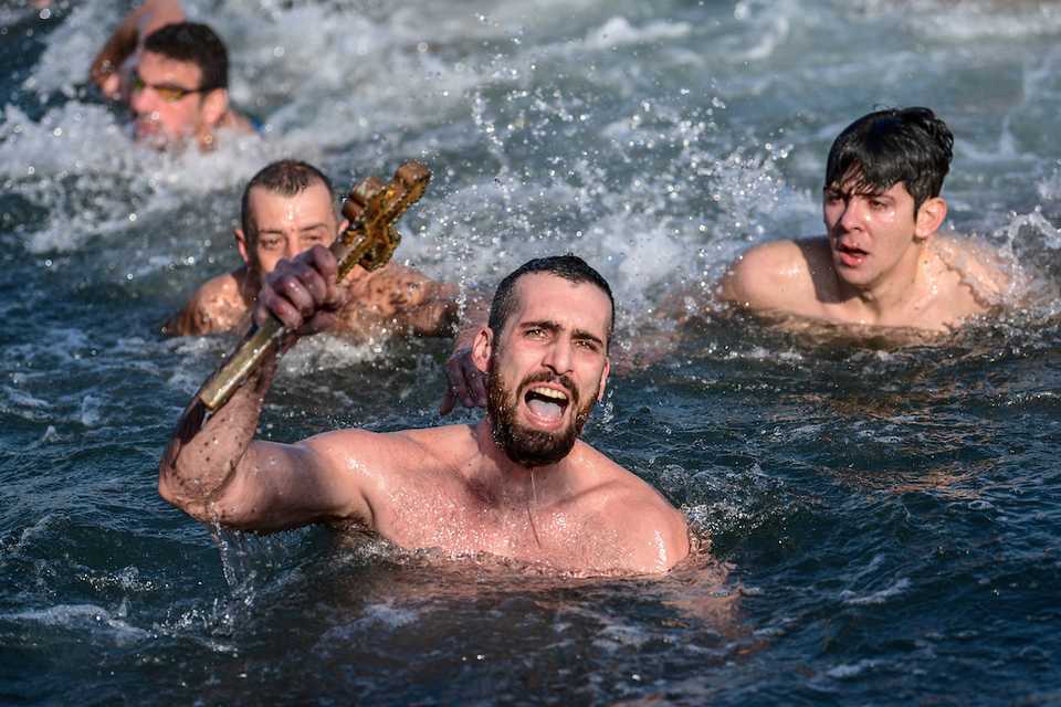 Greek Orthodox swimmer Nicolaos Solis (C) holds a wooden cross retrieved from the Bosphorus river's Golden Horn, as part of celebrations of the Epiphany day at the Church of Fener Orthodox Patriarchate in Istanbul, on January 6, 2018.