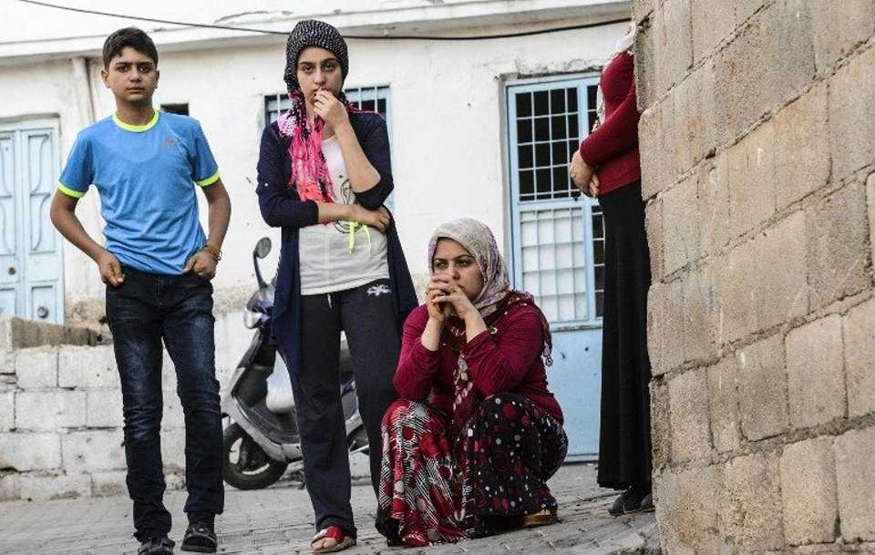People stand near the site of the explosion behind a police cordon following a late night attack on a wedding party that left 50 dead in Gaziantep in southeastern Turkey near the Syrian border on August 21, 2016. 
