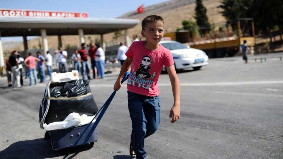 A Syrian refugee child enters Turkey from border, carrying his belongings on January 14, 2016.