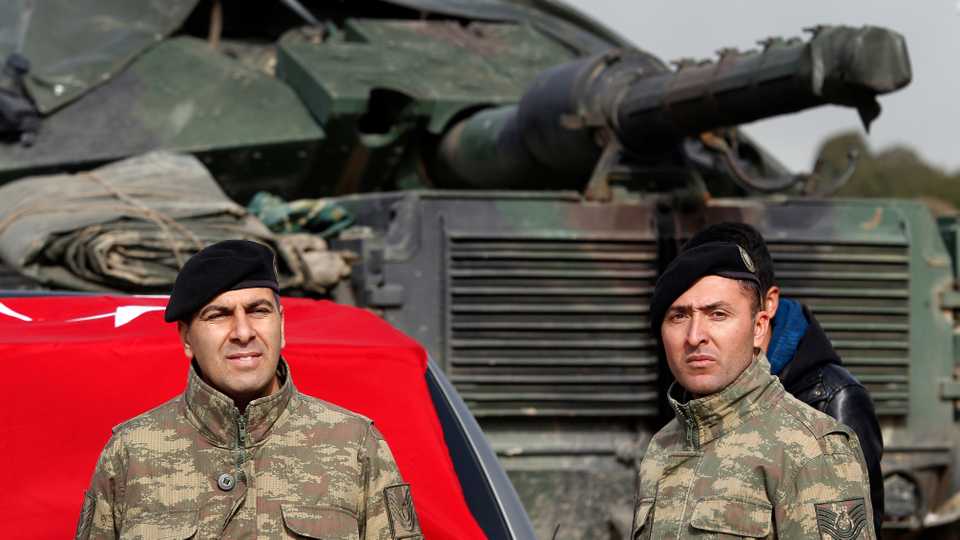 Turkish Army officers stand next to their tank on the border with Syria, January 22, 2018.
