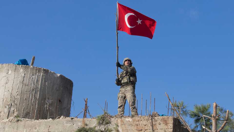 A Turkish soldier waves Turkish flag at Mount Bursaya after Turkish Military and FSA fighters liberated the strategic peak from YPG/PKK.