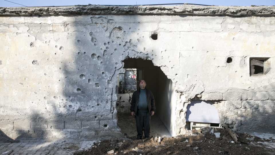A man stands under a demolished wall, which was destroyed after YPG fired 7 rockets since January 31 from Syria's northwest Afrin region, February 1, 2018.