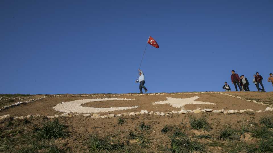 A Turkish man paints a Turkish flag on a hill near his home in Reyhanli district of Hatay in support of 'Operation Olive Branch' launched in Syria's Afrin.