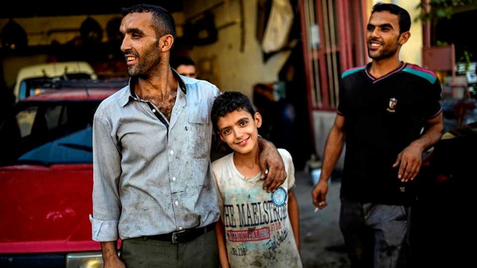 Muhammed, a Syrian refugee child, poses with his father Abdo as they work at an auto mechanic repair shop in Kilis, Turkey. September 6, 2016.