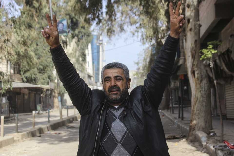 A local resident makes v sign as he greets Free Syrian Army members in Afrin town center on March 18, 2018.