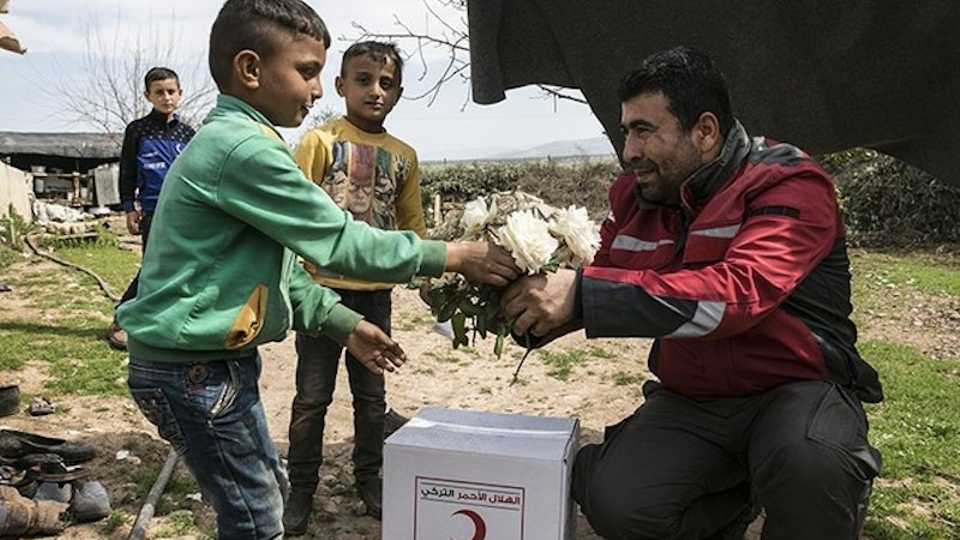 A children gives flowers to a Turkish Red Crescent worker in Nasiriyah village near the town of Jandaris, southern Afrin, Syria, on March 11, 2018