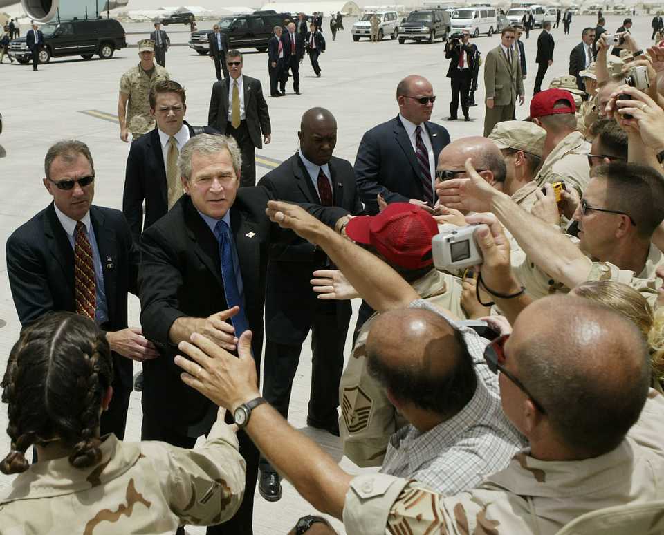 President Bush reaches out to cheering American troops at Al Udeid air base in Doha, Qatar, as he prepares to board Air Force One for a return flight to Washington, Thursday June 5, 2003.