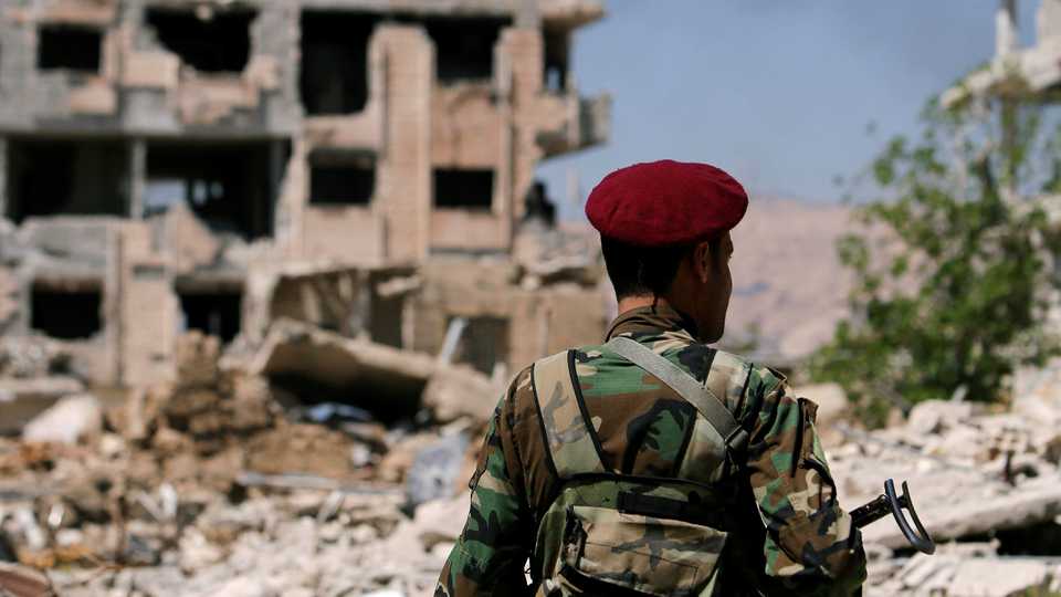 A member of Syrian regime forces stands guard near destroyed buildings in Jobar, eastern Ghouta, in Damascus, Syria on April 2, 2018.