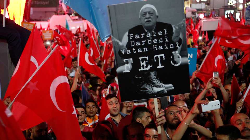Supporters of Turkish President Recep Tayyip Erdogan hold a portrait of Fethullah Gulen, a US-based Muslim cleric. during a pro-government rally in Ankara, Turkey, Wednesday, July 20, 2016. The Turkish words read 