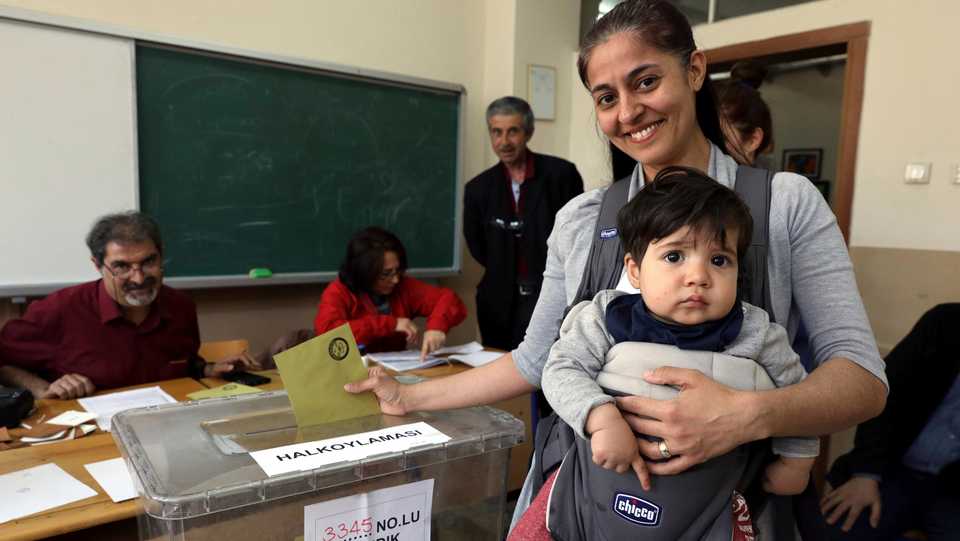 In this April 16, 2017 file photo, a Turkish woman holds her baby as she casts her vote at a polling station in Ankara, Turkey.