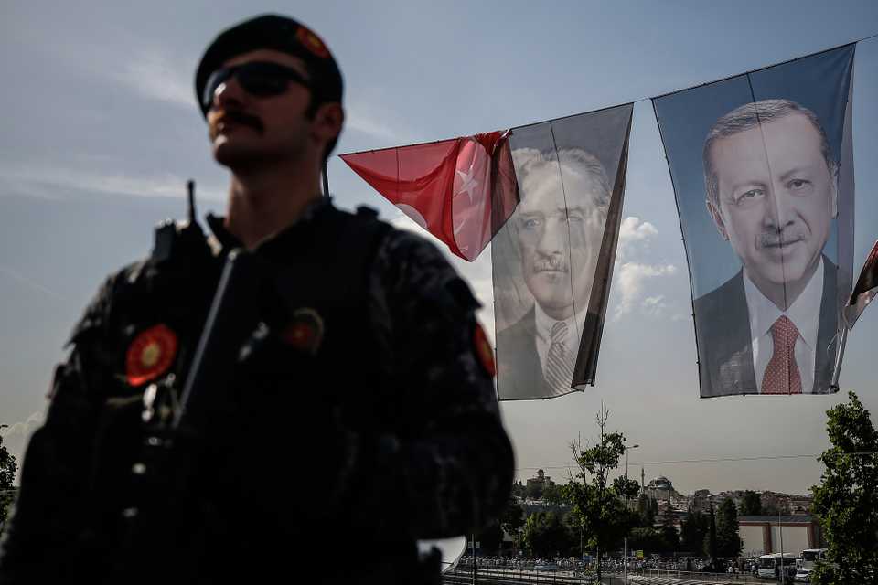 Backdropped by photographs of Mustafa Kemal Ataturk, (C), modern Turkey's founder and Turkey's current President Recep Tayyip Erdogan, (R), a Turkish police officer stands guard at a security checkpoint in Istanbul, on May 18, 2018.