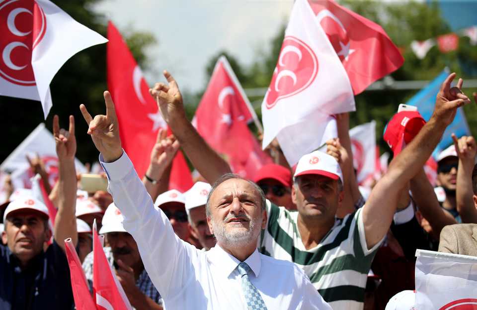 Supporters of Turkey's nationalist MHP make their party's signature gesture as leader Devlet Bahceli delivers a campaign speech in Ankara, June 23, 2018.