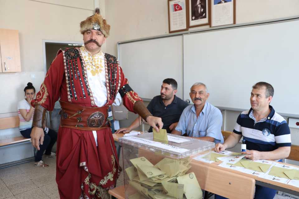 A voter dressed in Ottoman-era janissary clothing casts his ballot at a polling station during the parliamentary and presidential elections in Denizli.