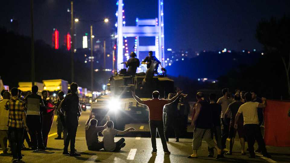 People take over a tank near the Fatih Sultan Mehmet bridge during clashes with military forces in Istanbul, on July 15, 2016.