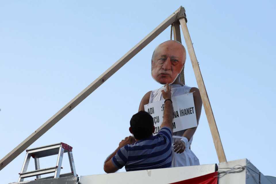 In this July 29, 2016 file photo, a man attaches a mask with the image of Fetullah Gulen, who is the leader of FETO, to a makeshift gallows at the Kizilay square in Ankara, Turkey.