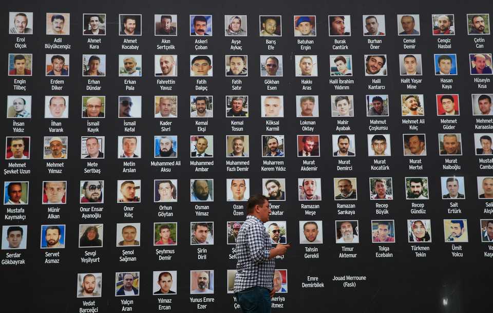 In this July 14, 2017, file photo, a man in Istanbul walks past a photos of victims of the July 15, 2016 coup attempt.