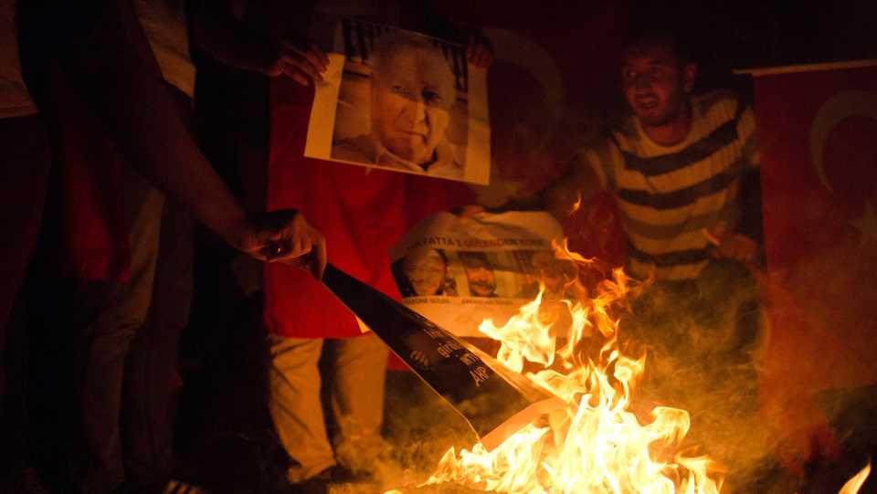 Turkish people burn pictures depicting of FETO leader Fetullah Gulen during a protest in Taksim Square, in Istanbul, Monday, July 18, 2016.