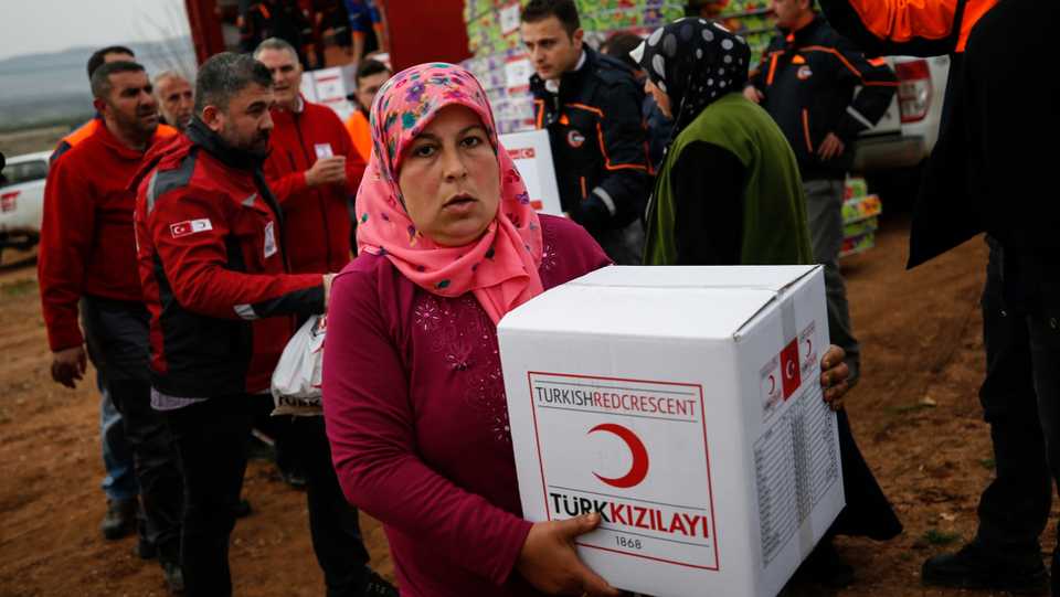 A woman receives humanitarian aid distributed by the Red Crescent, in Mersewa village, in the greater Afrin district, Syria, during a Turkish government-organised media tour into northern Syria, Saturday, March 3, 2018.