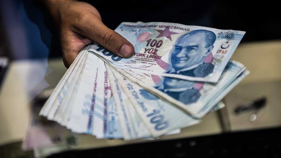 A teller holds Turkish lira banknotes at a currency exchange office in Istanbul on August 13, 2018.