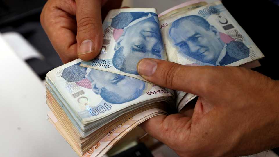 A money changer counts Turkish lira banknotes at a currency exchange office in Istanbul, Turkey on August 2, 2018.
