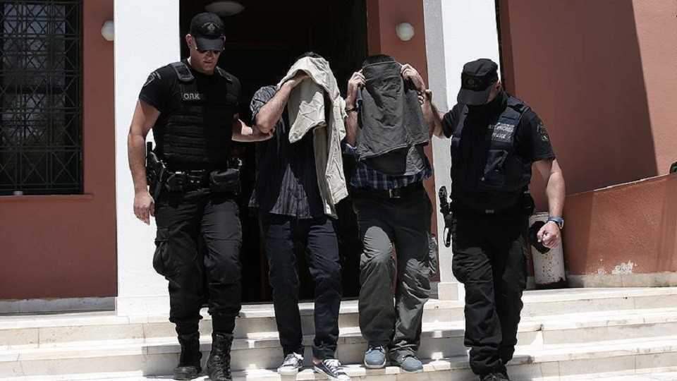 Greek security officers escort two of the coup-linked soldiers out of a courthouse.