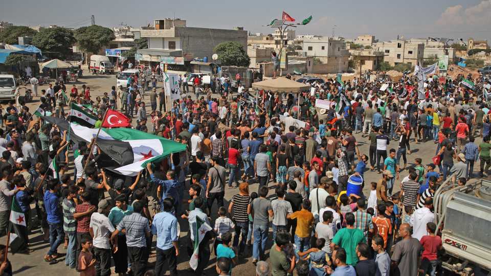 Syrians wave opposition and Turkish flags during a demonstration against the Syrian regime in the opposition and rebel-held town of Hazzanu, about 20 kilometres northwest of the city of Idlib, on September 21, 2018.
