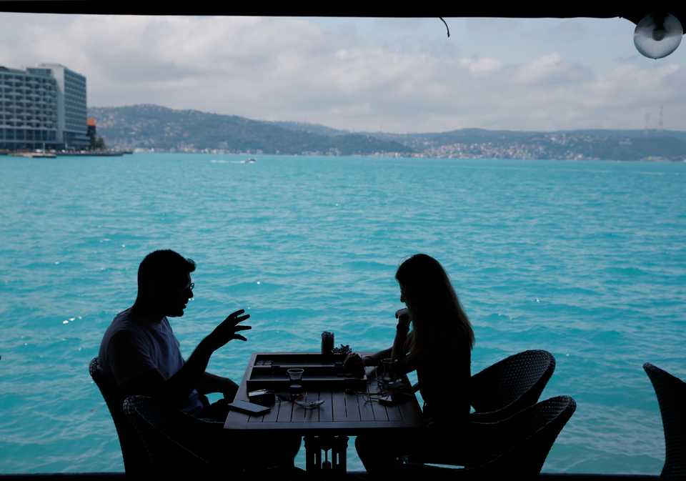 People play backgammon in a coffee shop by the Bosphorus Strait. Turkish media report a significant part of the Black Sea and the Bosphorus has turned turquoise due to phytoplankton. June 14, 2017.