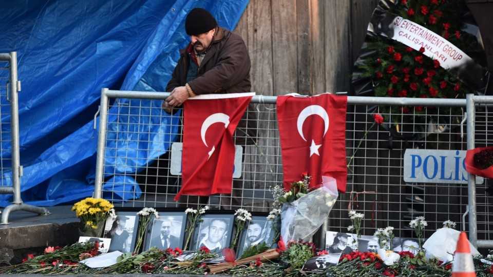 A man hangs a Turkish national flag in front of the Reina nightclub on January 2, 2017 in Istanbul, one day after a gunman killed 39 people at the upmarket venue.