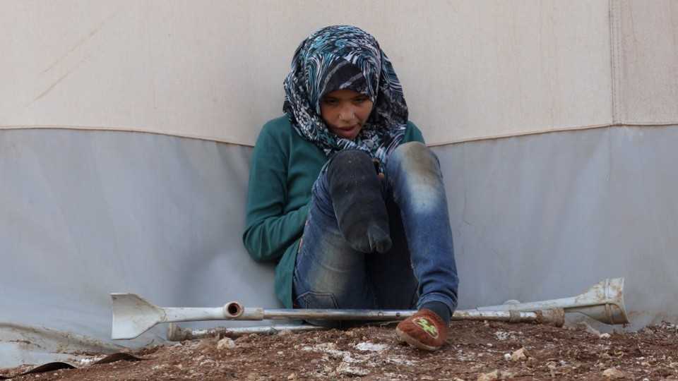 An internally displaced Syrian girl with an amputated leg checks her phone at the Bab Al-Salam refugee camp, near the Syrian-Turkish border, northern Aleppo province, Syria January 19, 2017.