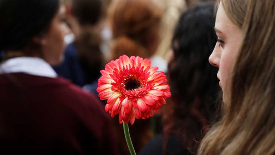 A student holds a flower during a vigil to commemorate victims of Friday's shooting, outside Masjid Al Noor mosque in Christchurch, New Zealand. March 18, 2019.